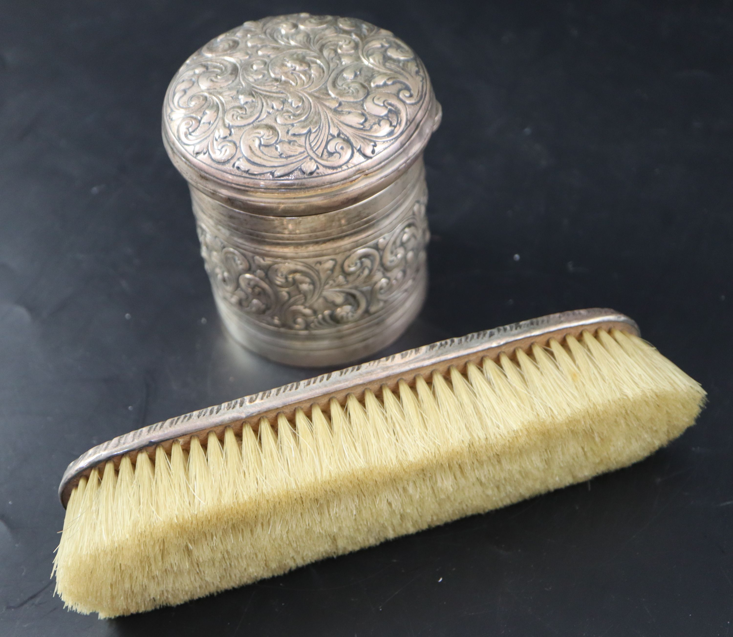 A Victorian embossed silver toilet jar, London, 1887, 93mm, 160 grams and a silver mounted clothes brush.